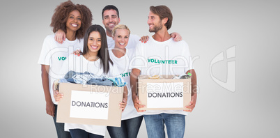 Composite image of happy group of volunteers holding clothes don