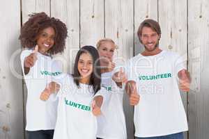 Composite image of happy group of volunteers giving thumbs up