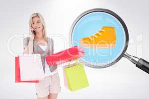 Composite image of happy blonde with shopping bags on the phone