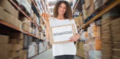 Composite image of happy volunteer holding a box of donations an