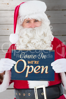 Composite image of cheerful santa claus holding page