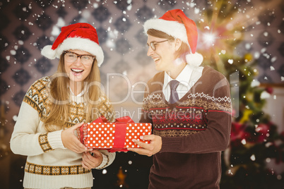 Composite image of geeky hipster couple holding present