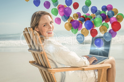 Composite image of gorgeous blonde sitting on deck chair using l