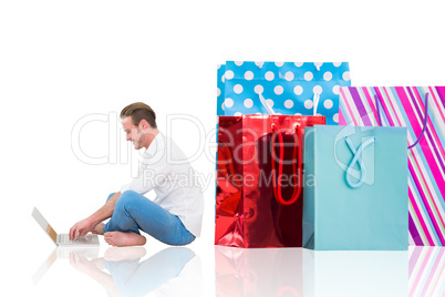 Composite image of smiling man using laptop with crossed legs