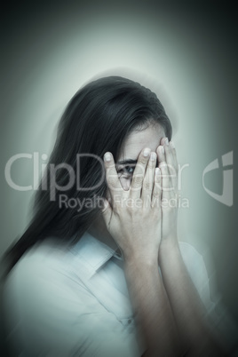 Composite image of portrait of woman peeking through fingers