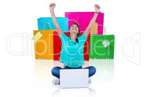 Composite image of woman with arms raised sitting by laptop on w
