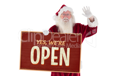 Composite image of santa holds a sign and is waving