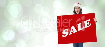 Composite image of pretty brunette in santa hat pointing white p