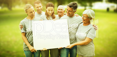 Composite image of happy volunteer family holding a blank