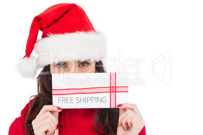 Composite image of festive brunette holding a gift