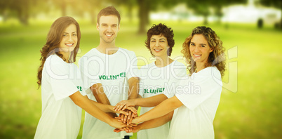 Composite image of smiling volunteer group piling up their hands