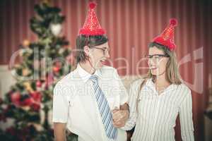 Composite image of happy geeky hipster couple with party hat