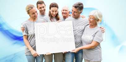 Composite image of happy volunteer family holding a blank