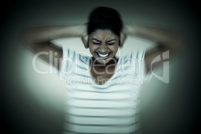 Composite image of angry woman covering ears
