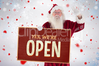 Composite image of santa holds a sign and is waving