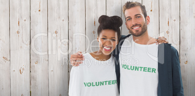 Composite image of portrait of two young volunteers with arms ar