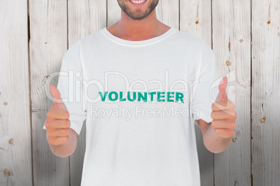 Composite image of man wearing volunteer tshirt giving thumbs up