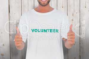 Composite image of man wearing volunteer tshirt giving thumbs up
