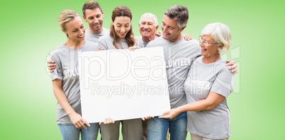 Composite image of happy volunteer family holding a blank