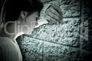 Composite image of sad pretty brunette leaning against wall