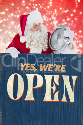 Composite image of santa holding a clock and sign