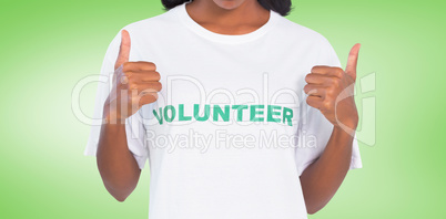 Composite image of woman wearing volunteer tshirt and giving thu