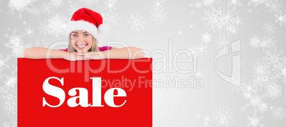 Composite image of festive blonde leaning on large poster