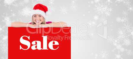 Composite image of festive blonde leaning on large poster
