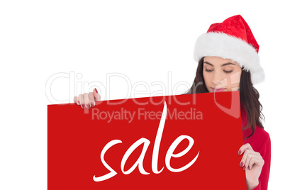 Composite image of beauty brunette in santa hat showing white po