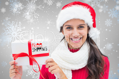 Composite image of festive brunette holding gift