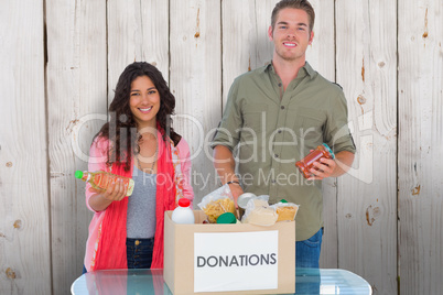 Composite image of smiling volunteers taking out food from donat