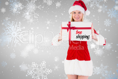 Composite image of festive blonde holding a gift