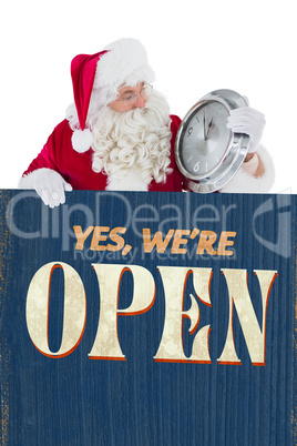 Composite image of santa holding a clock and sign