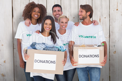 Composite image of happy group of volunteers holding clothes don