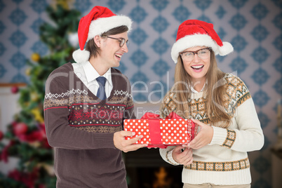 Composite image of geeky hipster couple holding present