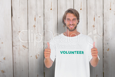 Composite image of happy man wearing volunteer tshirt giving thu