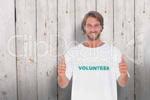 Composite image of happy man wearing volunteer tshirt giving thu