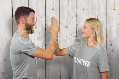 Composite image of smiling volunteer doing high five in office
