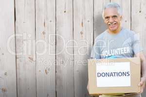 Composite image of happy volunteer senior holding donation box