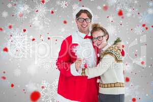 Composite image of geeky hipster in santa costume hugging his gi