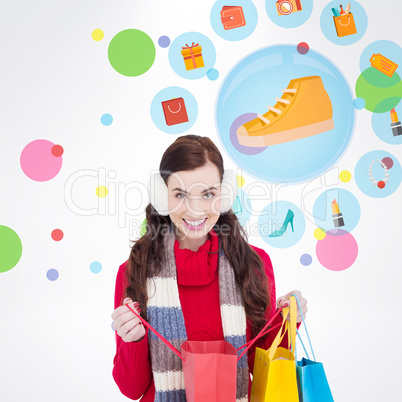 Composite image of brunette in winter clothes holding shopping b