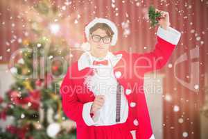 Composite image of geeky hipster in santa costume holding mistle