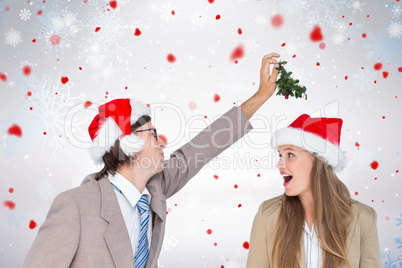 Composite image of man wearing santa hat and holding mistletoe w