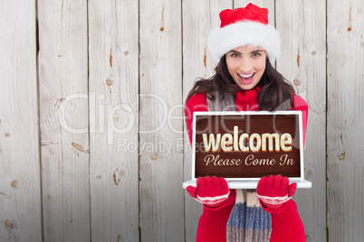 Composite image of festive brunette showing a laptop