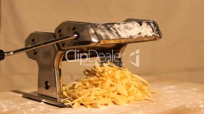 pasta maker with noodles spinning on a wooden board
