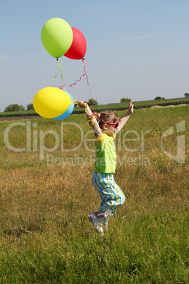 little girl running on field with balloons
