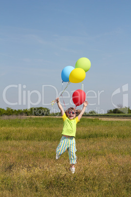 happy little girl with balloons jumping on field