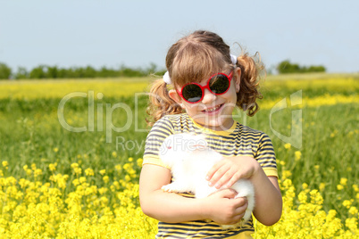 little girl with bunny pet in yellow field