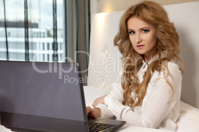 businesswoman using laptop while lying on bed