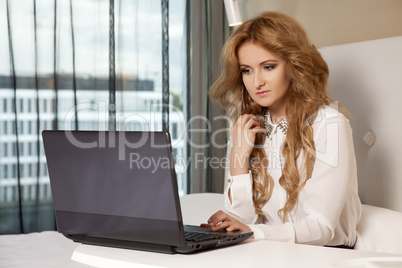 businesswoman using laptop while lying on bed